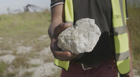 A worker holds a lump of lithium ore in Manono DRC 2023