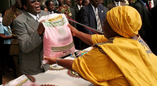 Robert Mugabe, hands out maize seed to a Zanu PF supporter