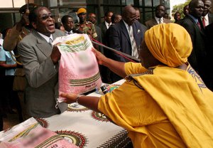 Robert Mugabe, hands out maize seed to a Zanu PF supporter